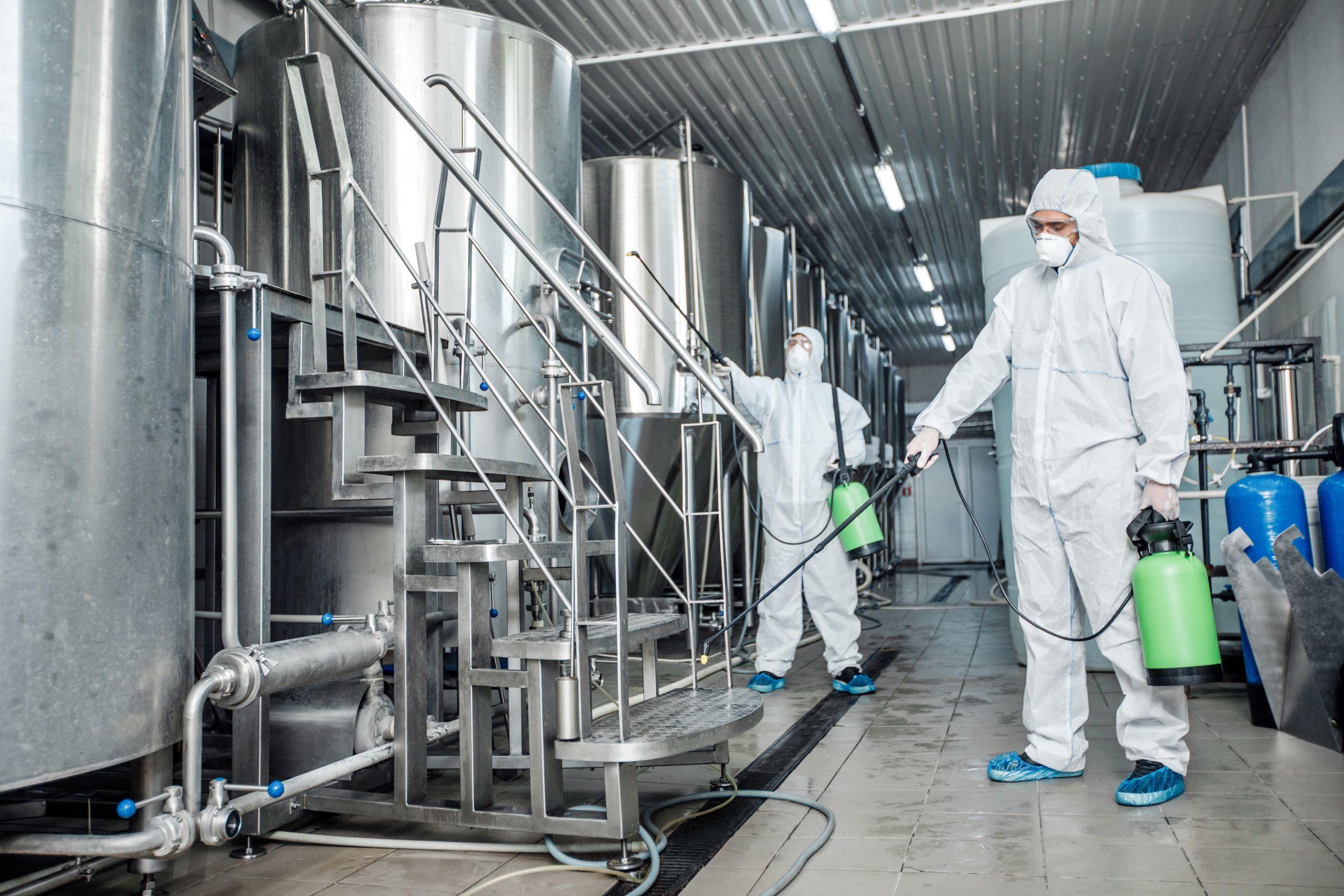 homens limpando fábrica para evitar contaminação cruzada